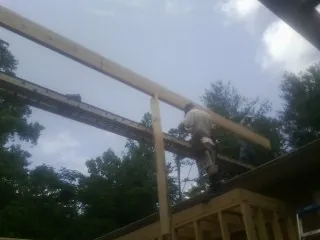 Carpenter setting a ridge beam over a new addition frame — Ice Dam Removal by Roofing Brothers in Northville