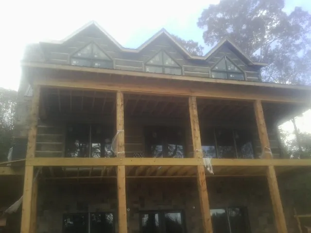 Dormers and porch framing on a large log home under construction — Roof Coating work by our crew in Northville