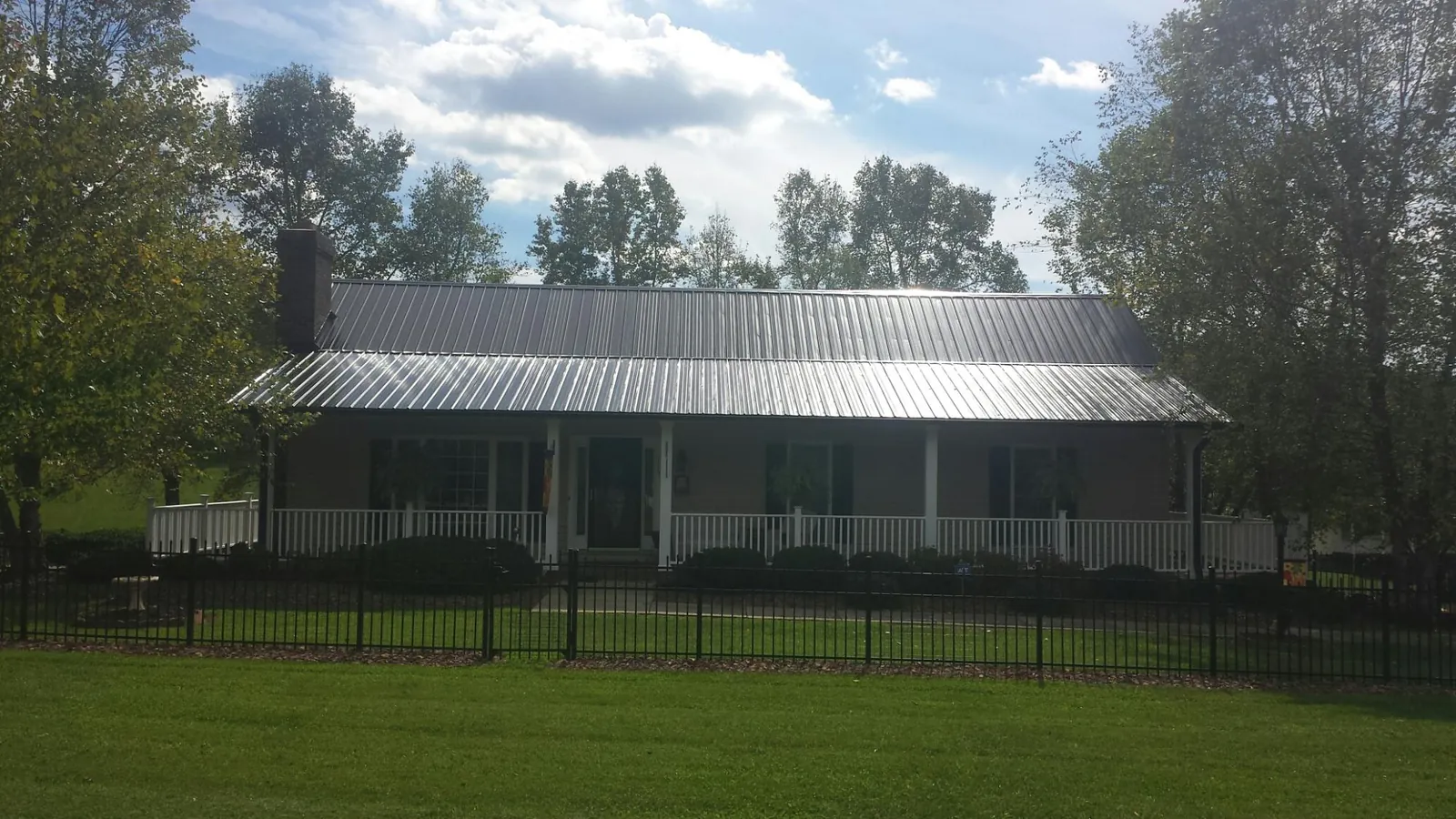 Gray metal roof on a brick ranch with a full width front porch — Gutter Guard Installation work by our crew in Northville