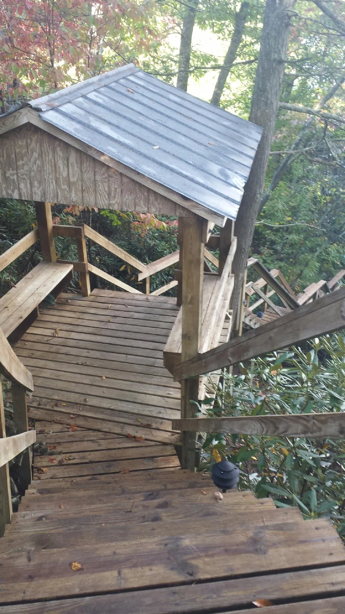 Metal roofed shelter over wooden steps on a wooded walkway — Skylight Repair & Installation work by our crew in Northville