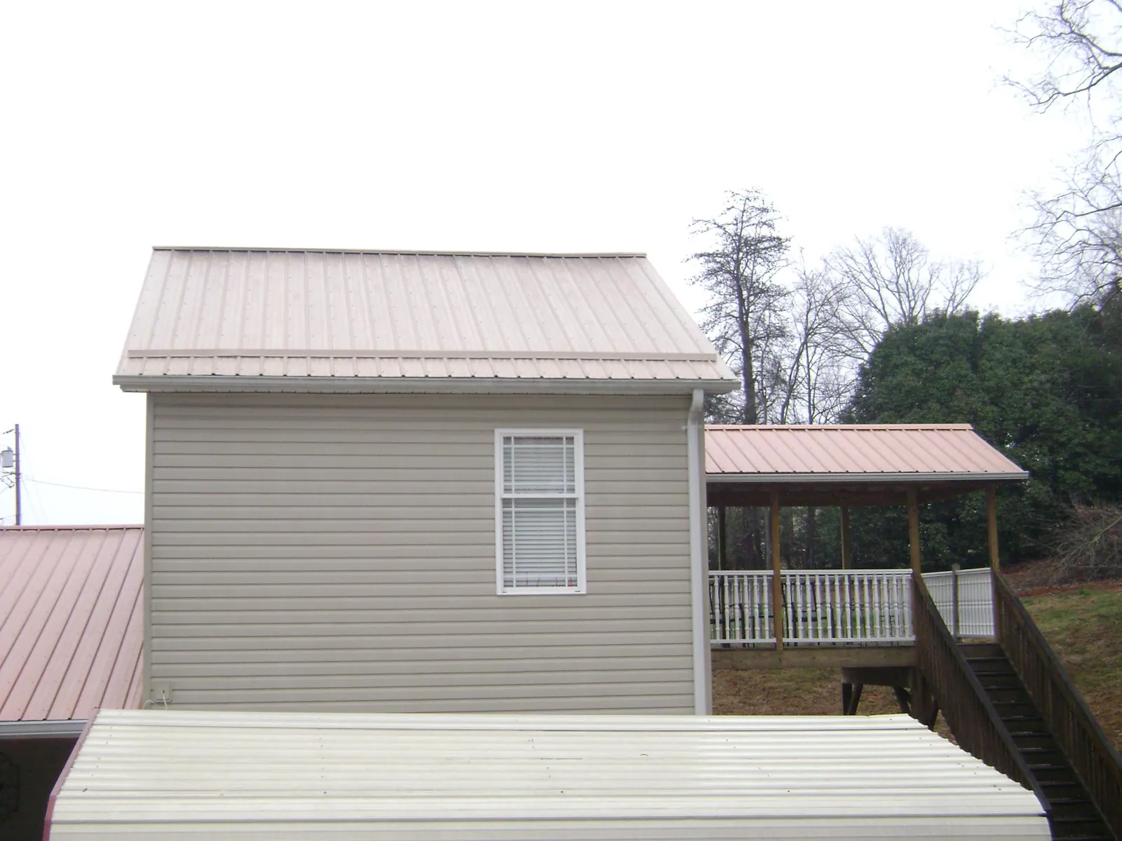 Tan metal roofs on a two story addition and attached porch, from a Roof Replacement job in Northville