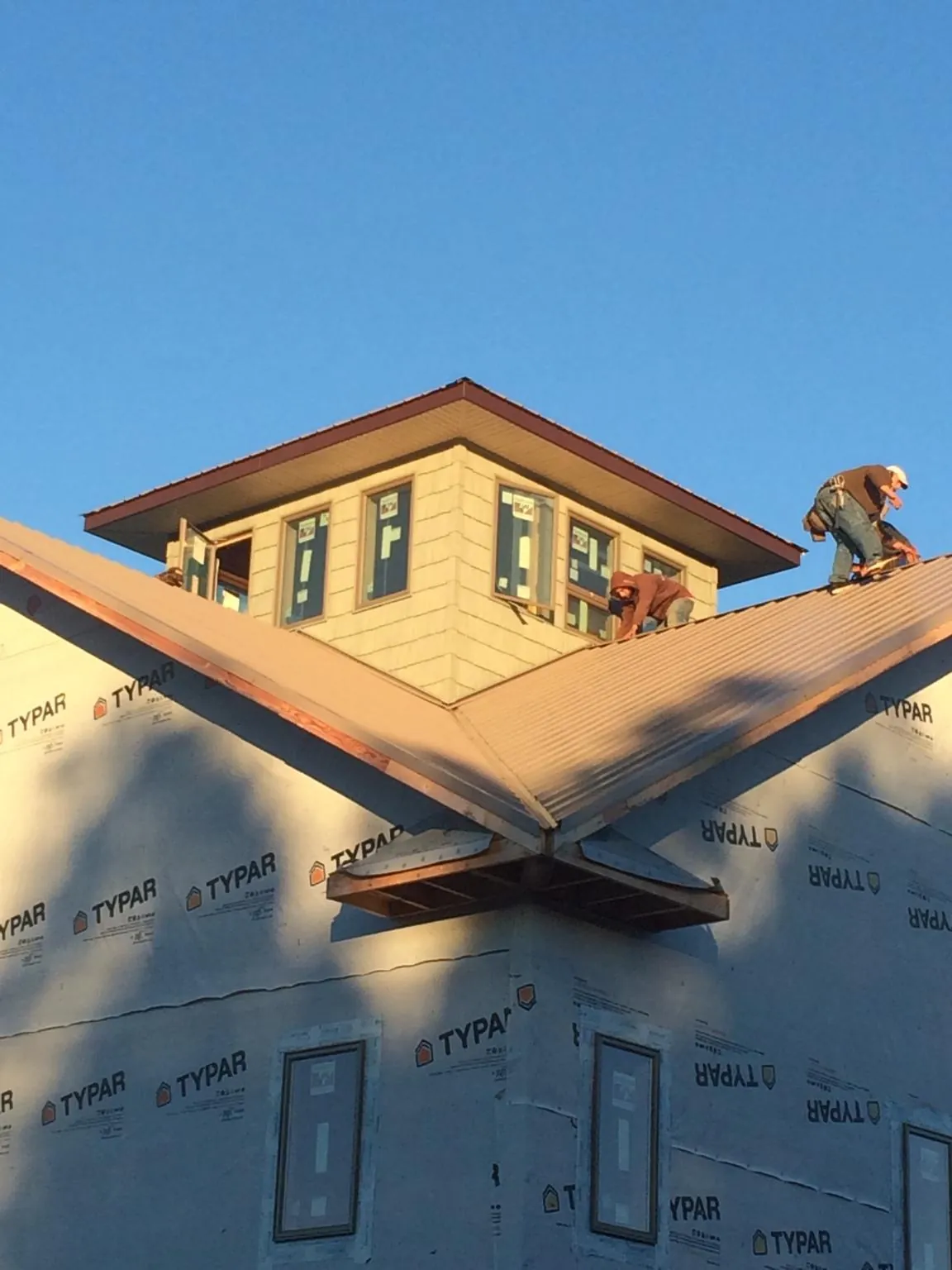 Roofers working around a rooftop cupola on a new metal roof at sunset — Roof Waterproofing in Northville by Roofing Brothers